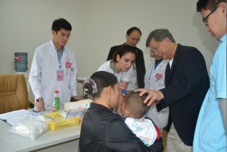 美國微笑聯(lián)盟副會長黃球綸在協(xié)助醫(yī)療隊(duì)牙科醫(yī)生對患兒做術(shù)前牙科檢查