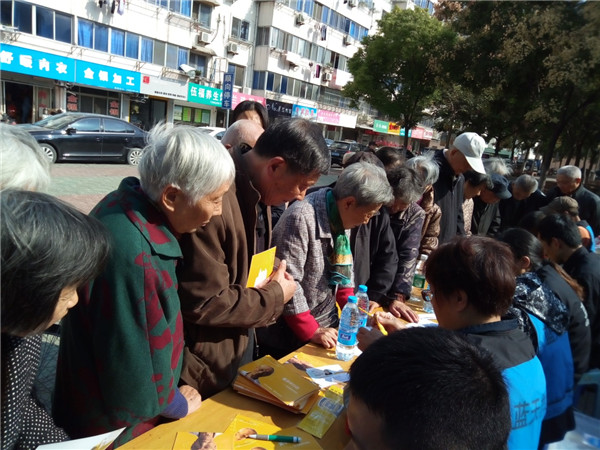 老人排隊咨詢，領取黃手環、定位帖與宣傳資料.jpg